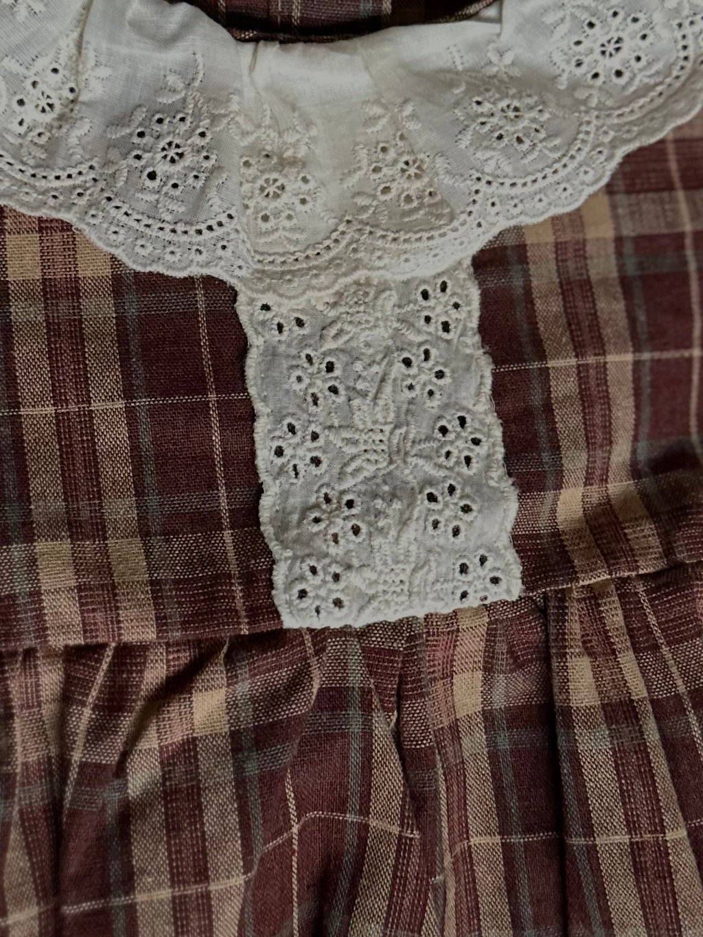 Lace details down front middle of 100% cotton Brownish plaid bubble romper with lace front and collar. 