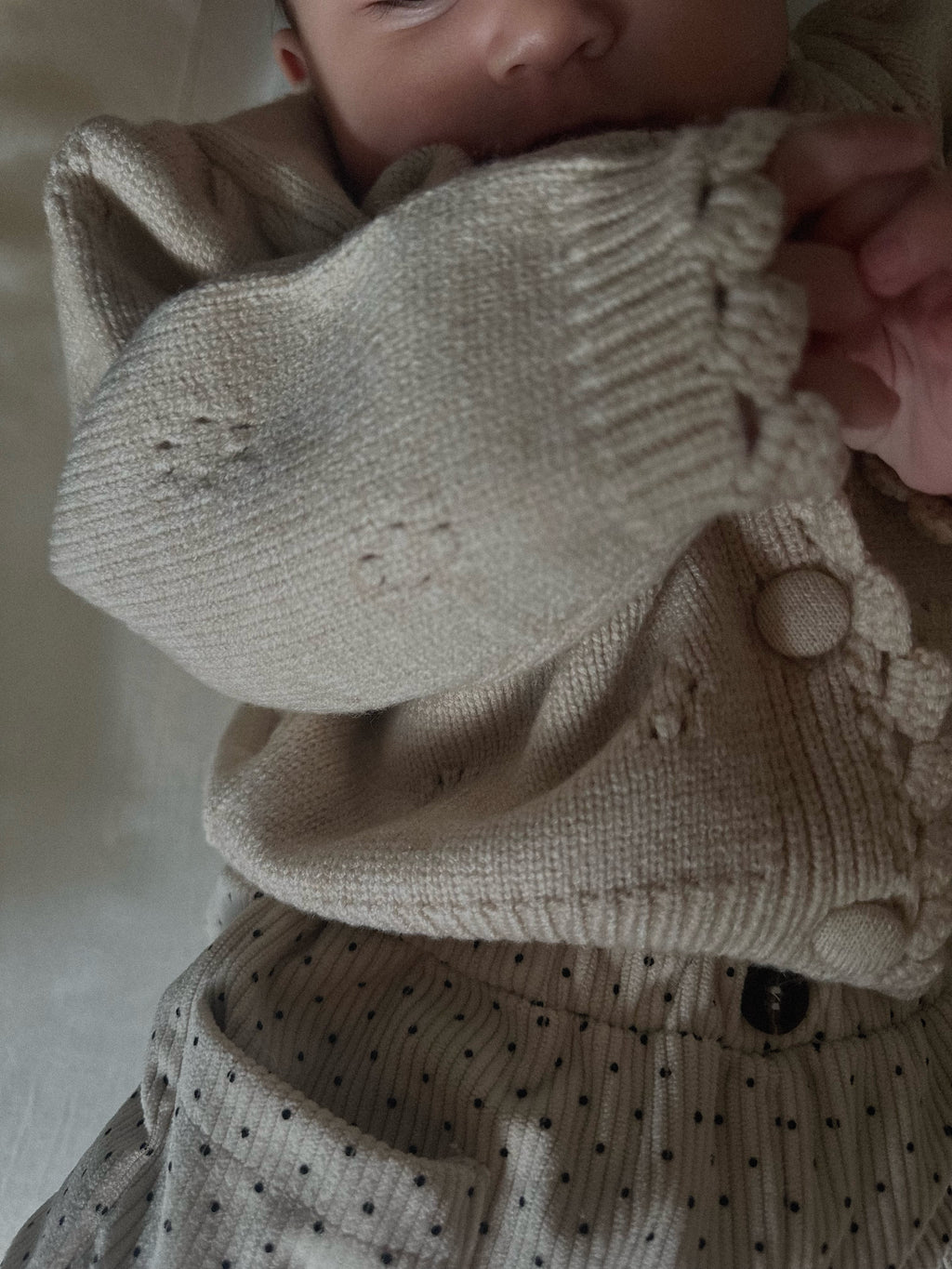 Apricot tan soft and thick polyester blend cardigan with buttons, pointelle design on baby.