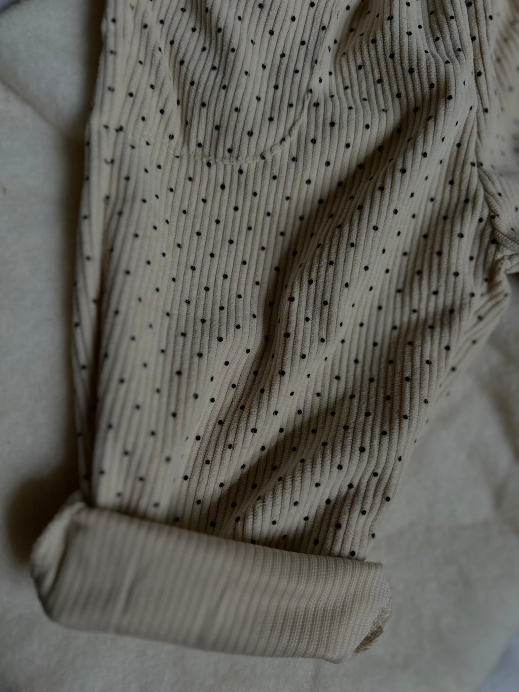 Cuffed hem of Light cream colored soft polka dot corduroy pants with button. 
