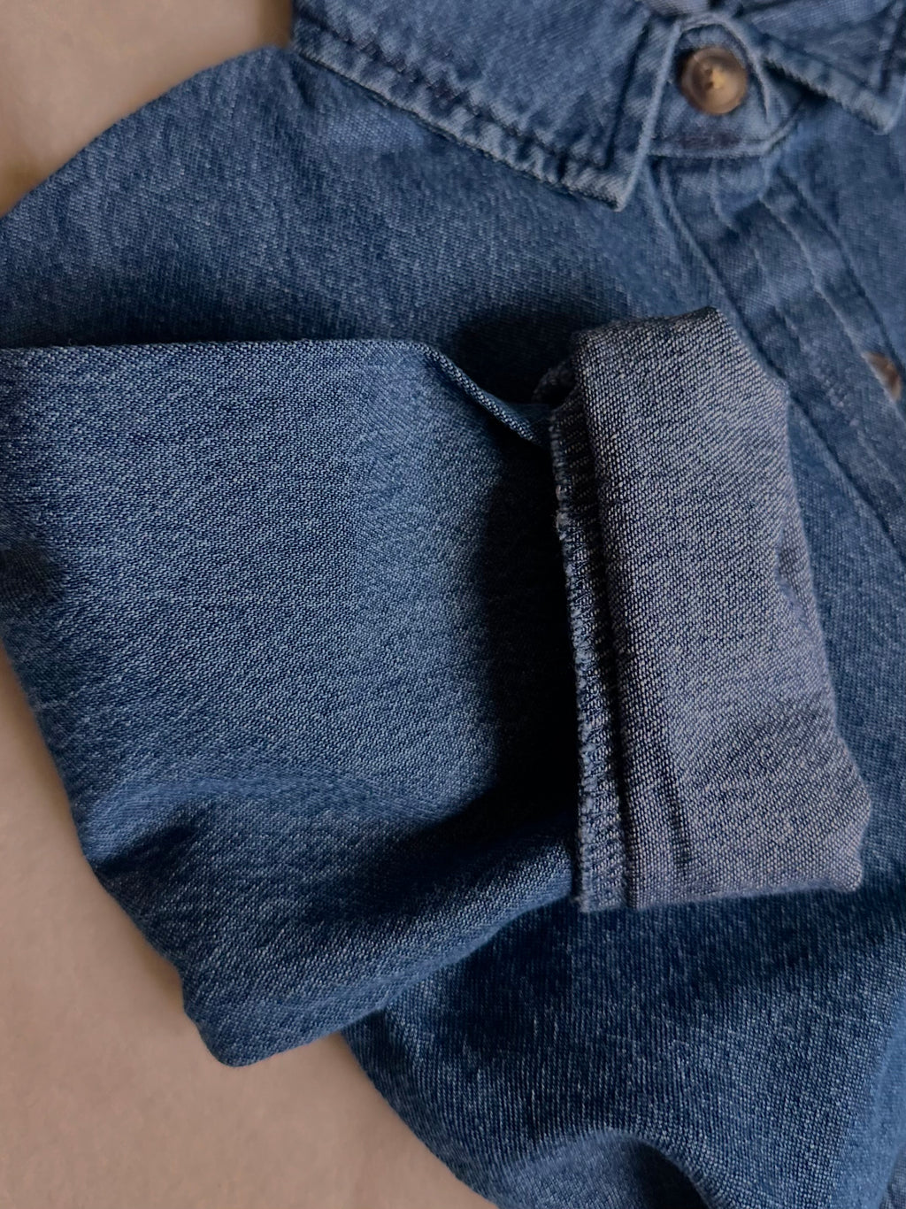 Light to medium wash 100% cotton denim shirt, long sleeve rolled up. 