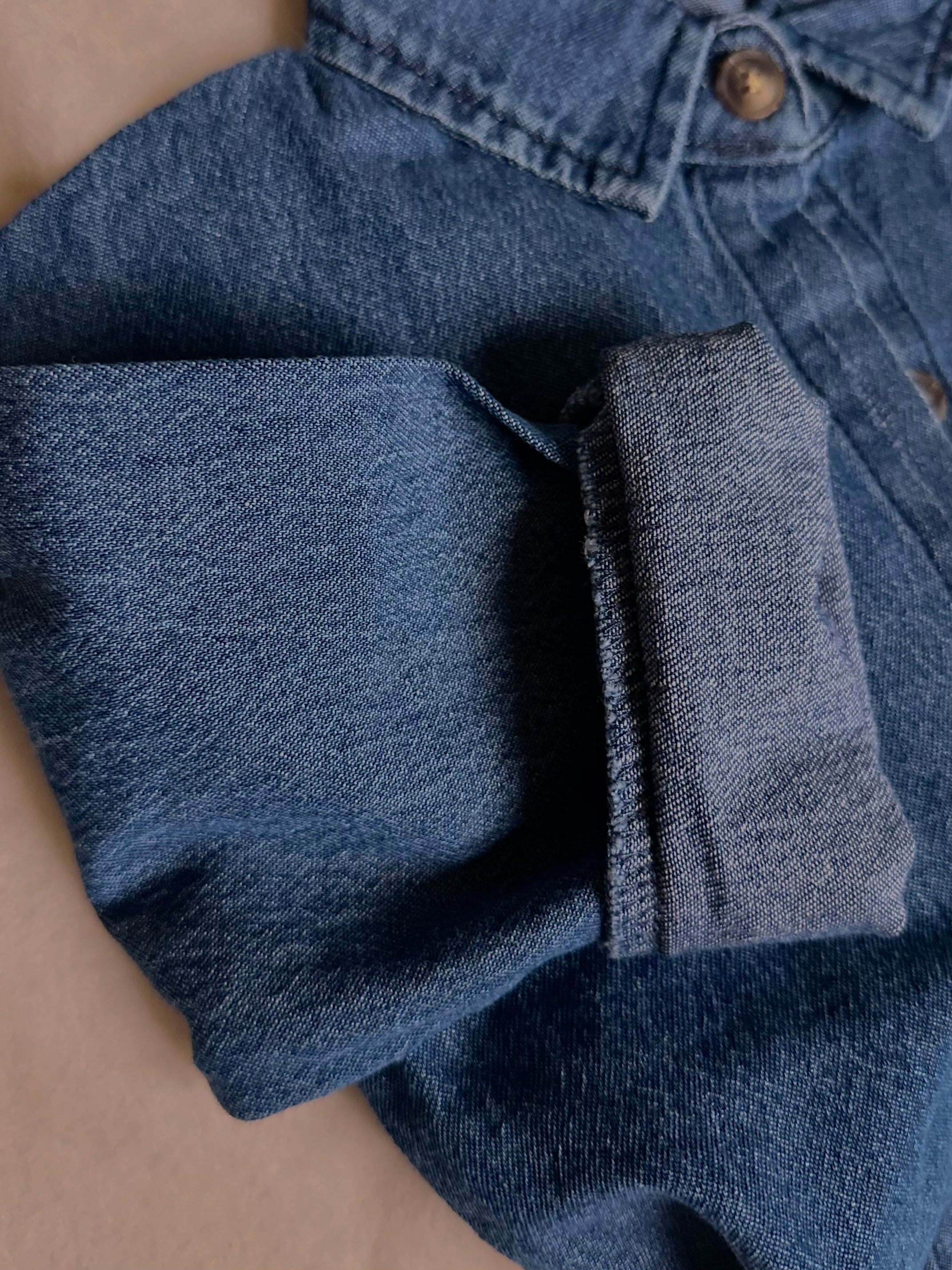 Light to medium wash 100% cotton denim shirt, long sleeve rolled up. 