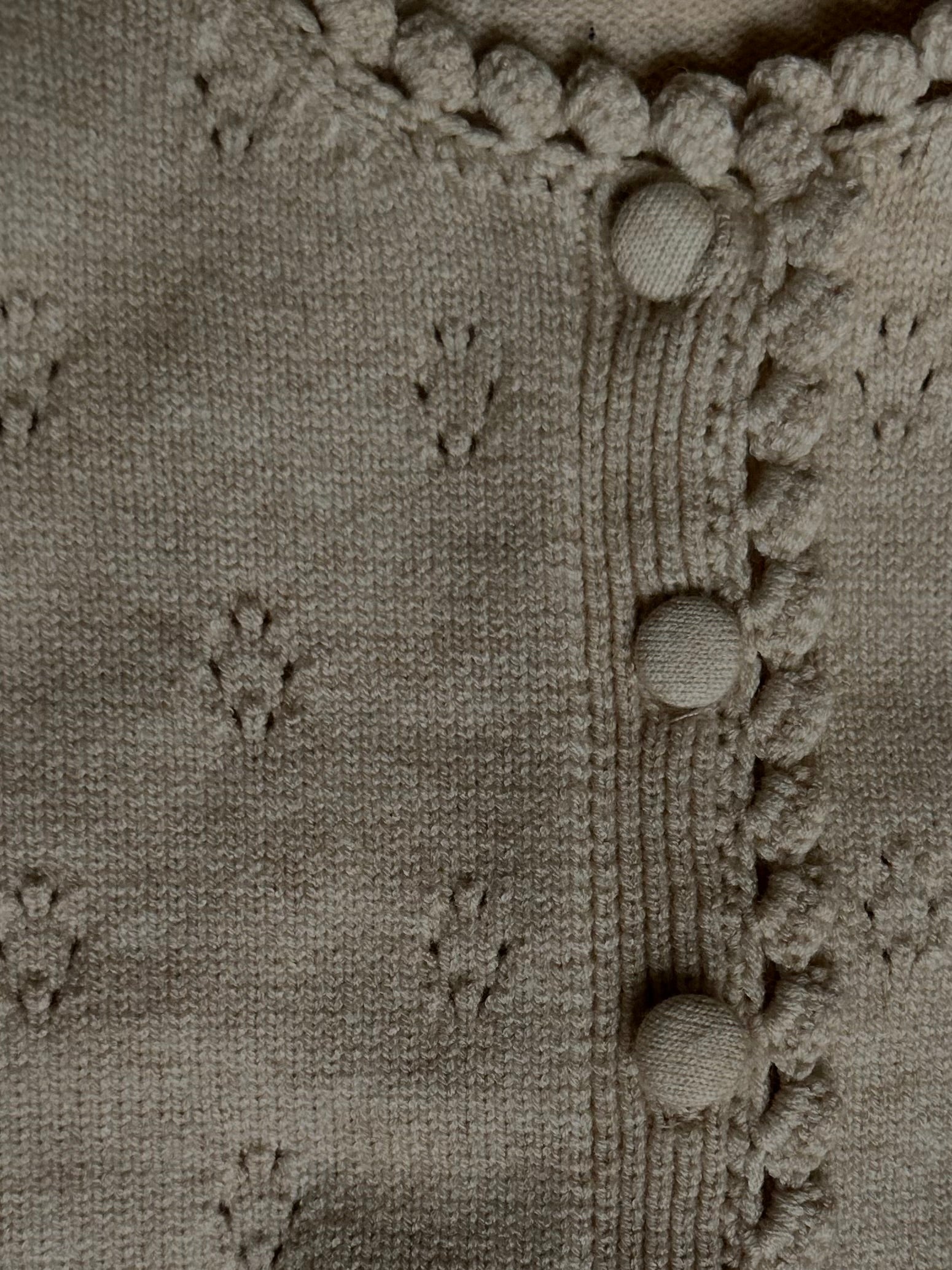 Details on apricot tan soft and thick cardigan with buttons, pointelle design. 