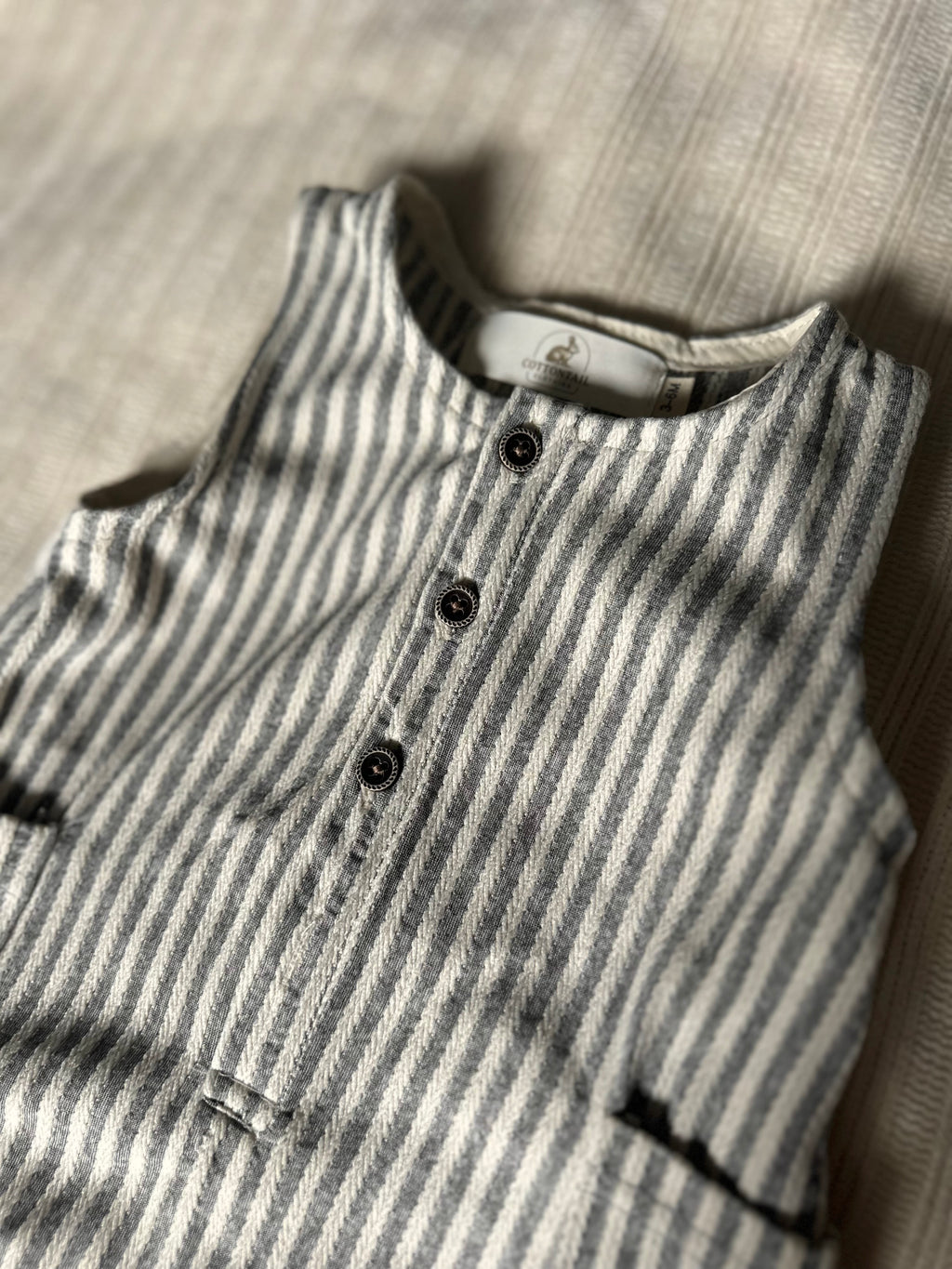 PinStriped baby boy romper cotton with buttons on a textured surface
