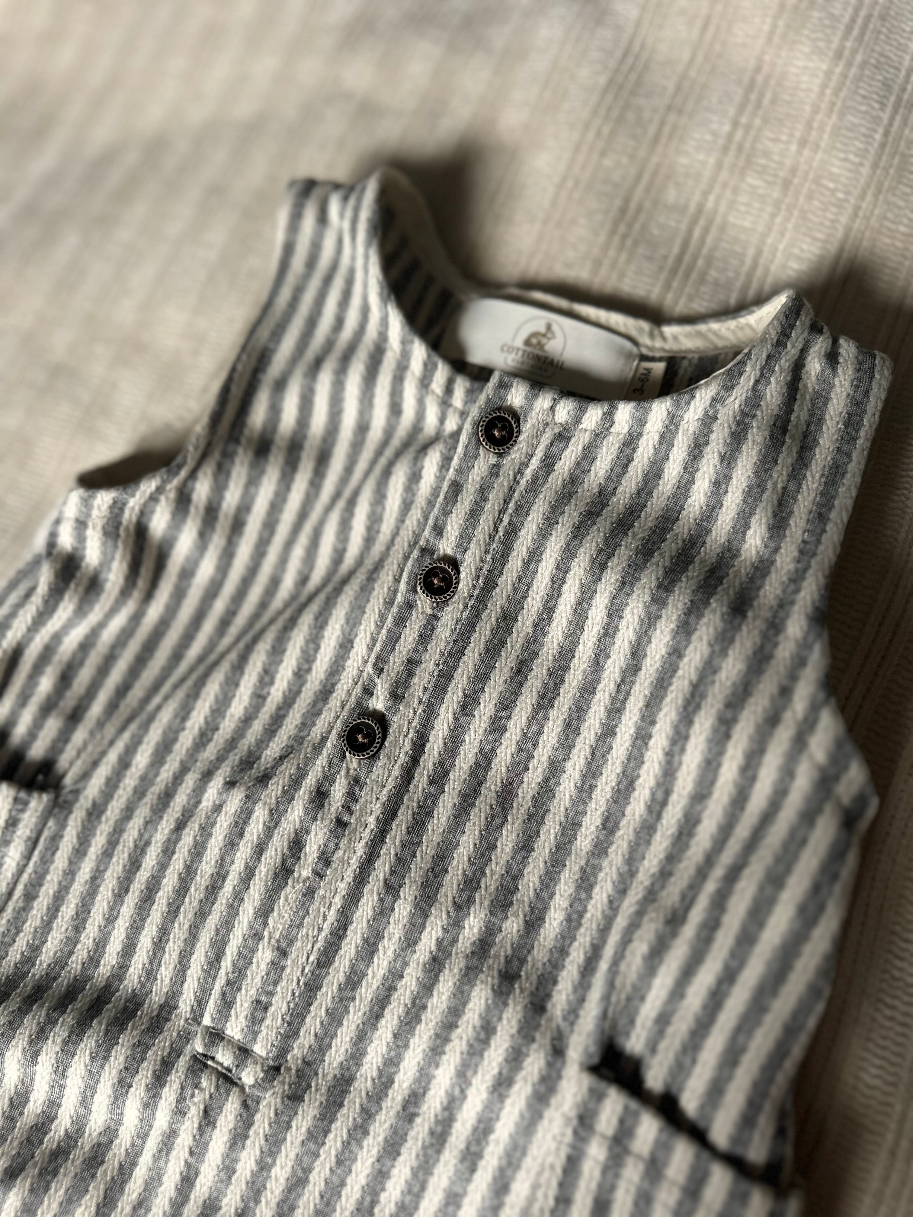 PinStriped baby boy romper cotton with buttons on a textured surface