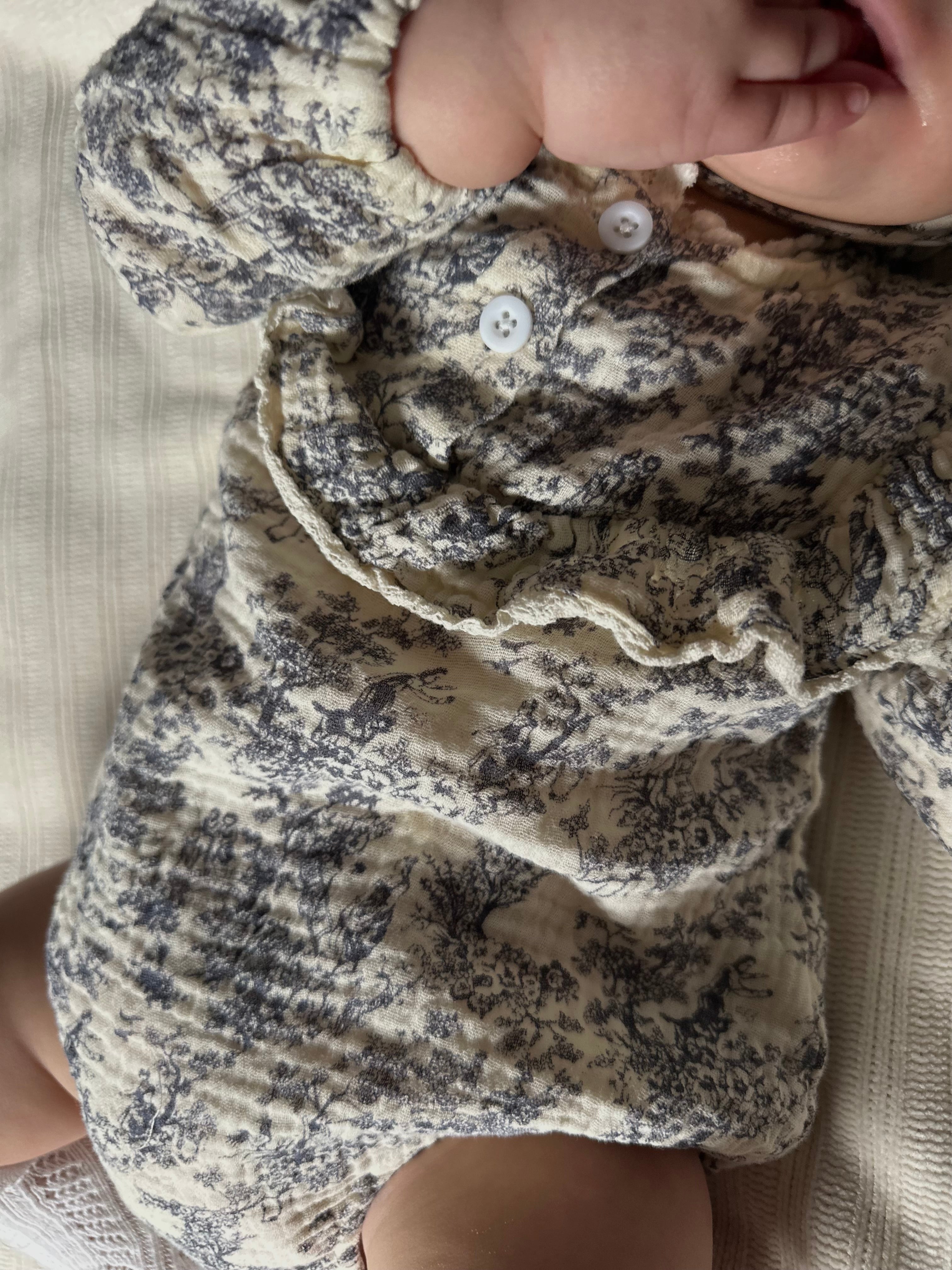 Close-up of a baby's blue gray floral-patterned romper