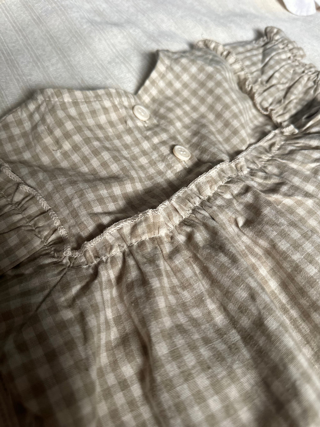 Close up details of 100% cotton tan colored gingham baby set top, back with buttons 