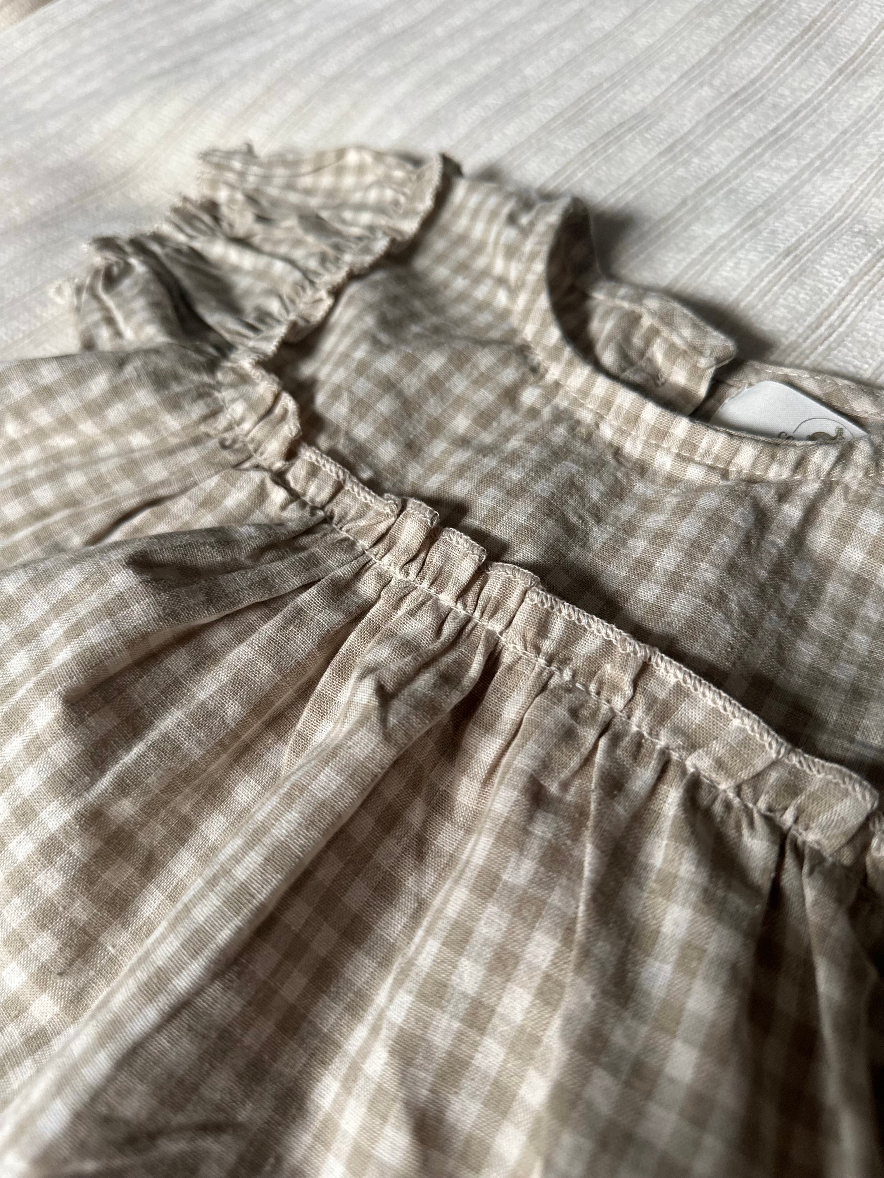 Close-up of a 100% cotton gingham tan set, but the top with ruffled details on a textured surface