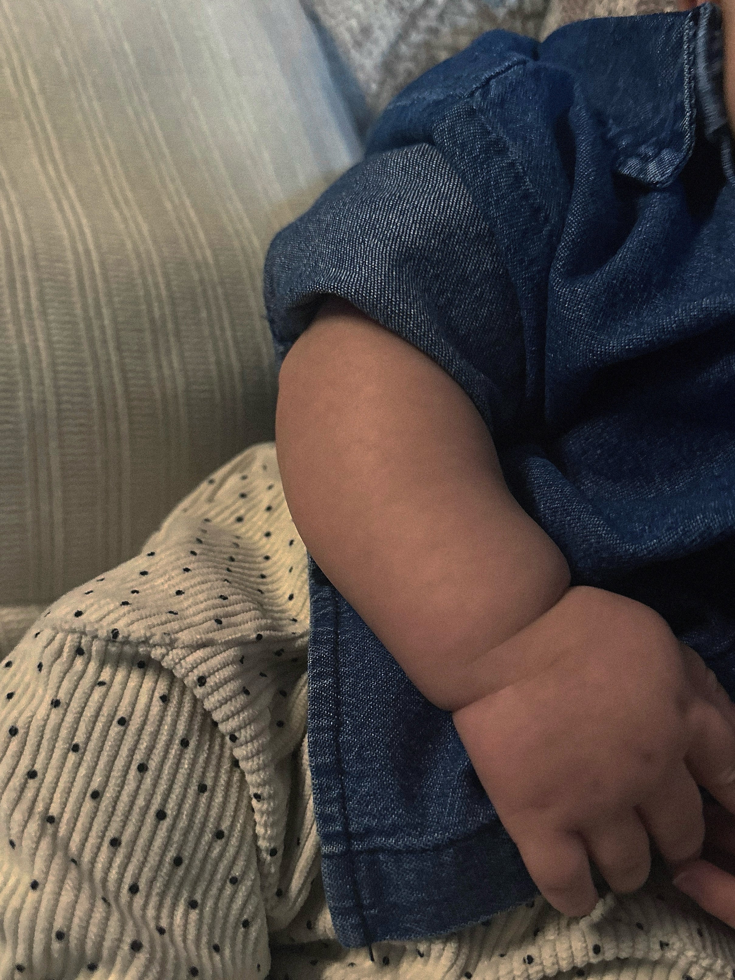 Baby wearing light to medium wash 100% cotton denim shirt, long sleeve, collar, buttons on baby and cream corduroy polka dot pants. 