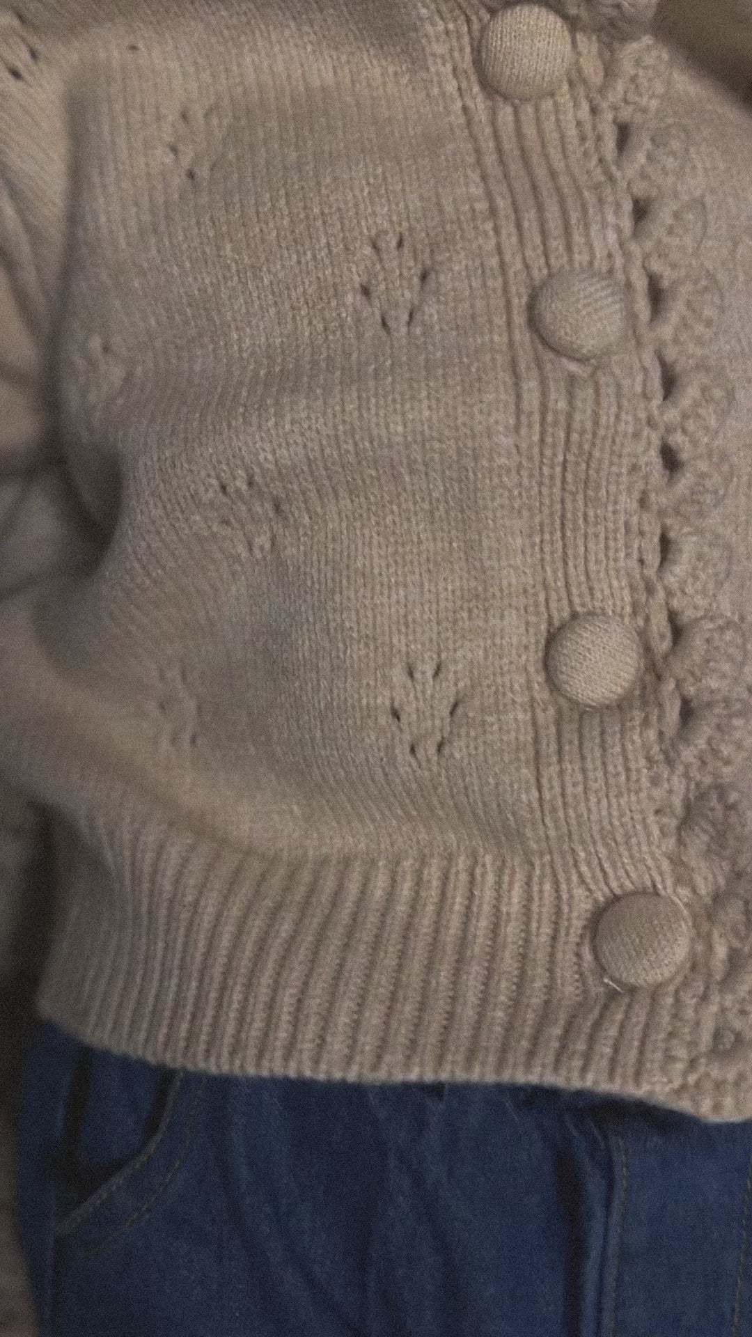 Video of Apricot tan soft and thick polyester blend cardigan with buttons, pointelle design on baby. 