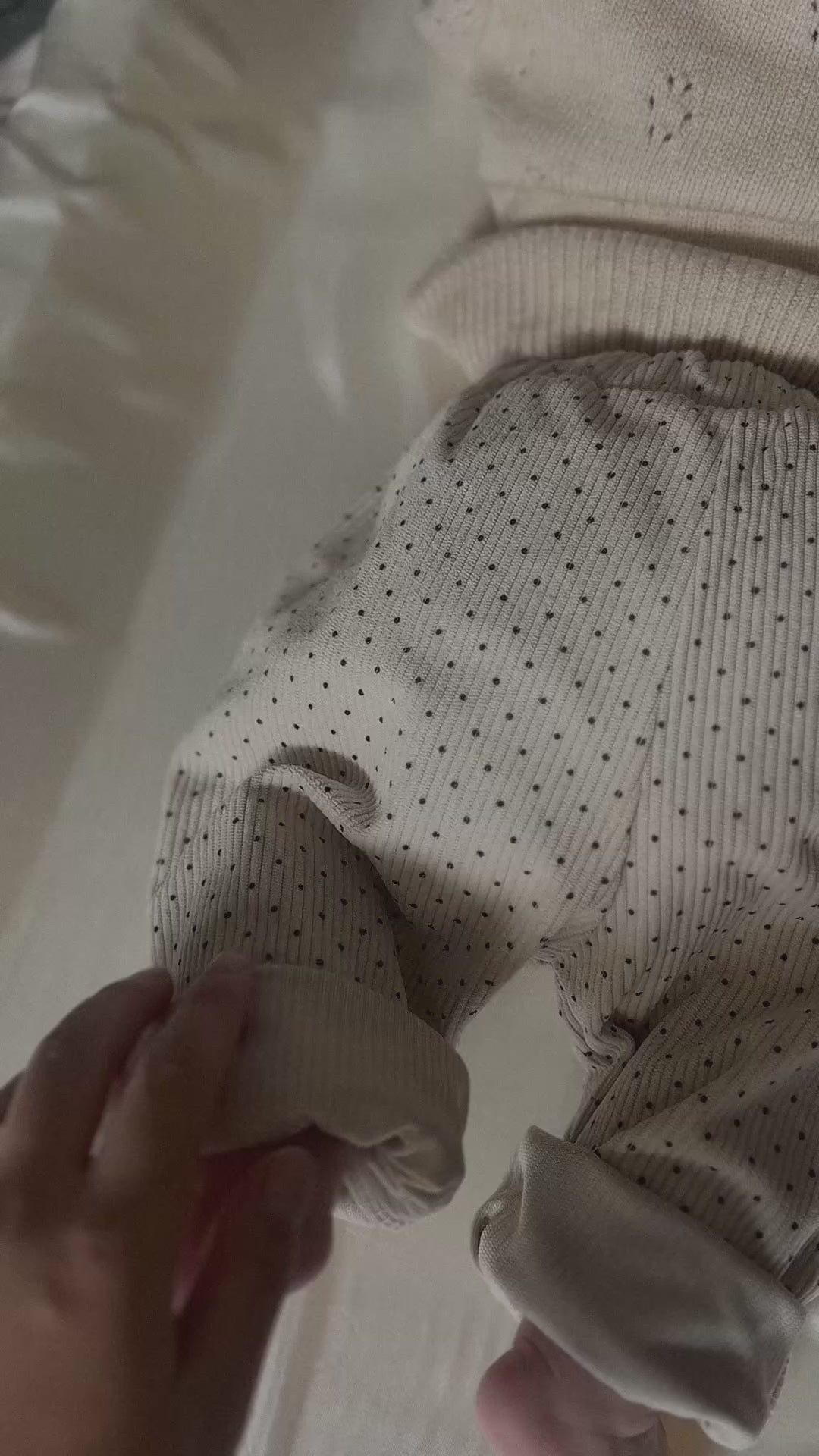 Video of back of baby wearing Light cream colored soft polka dot corduroy pants with button. 